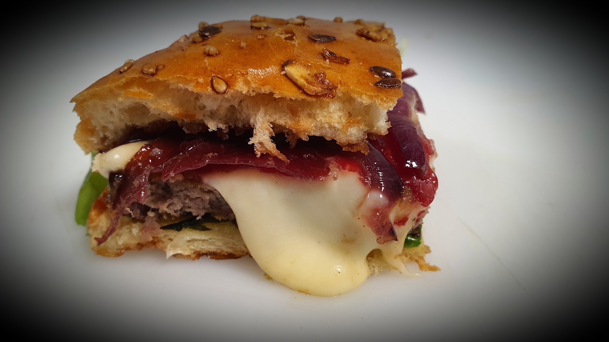 Close-up van een burger met gesmolten kaas en rode ui confit